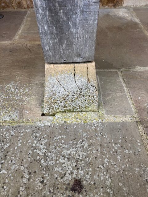 Pre-cast concrete staddle stone cracked and crumbling under the load of an oak post